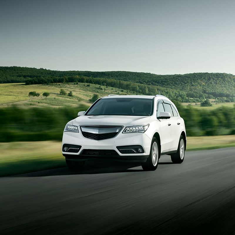 SUV blanc de luxe roulant sur route au milieu de collines vertes. SUV blanc circulant rapidement sur une route asphaltée au milieu d'un paysage de collines et de forêts verdoyantes.