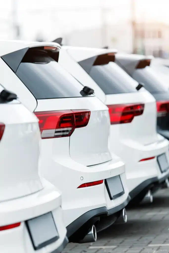 Ligne de voitures blanches neuves, design moderne sport. Ligne de voitures blanches neuves stationnées. Arrière des hayons, feux LED rouges et doubles sorties d'échappement sport.